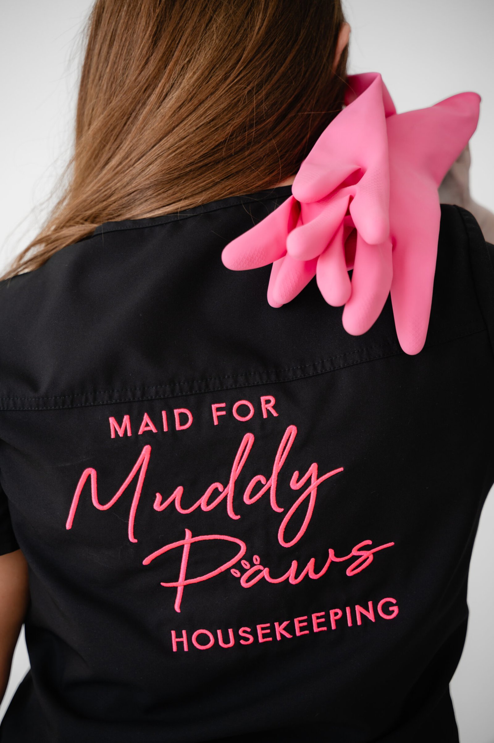 Maid for Muddy Paws housekeeping uniform with pink gloves showing professional cleaning service branding